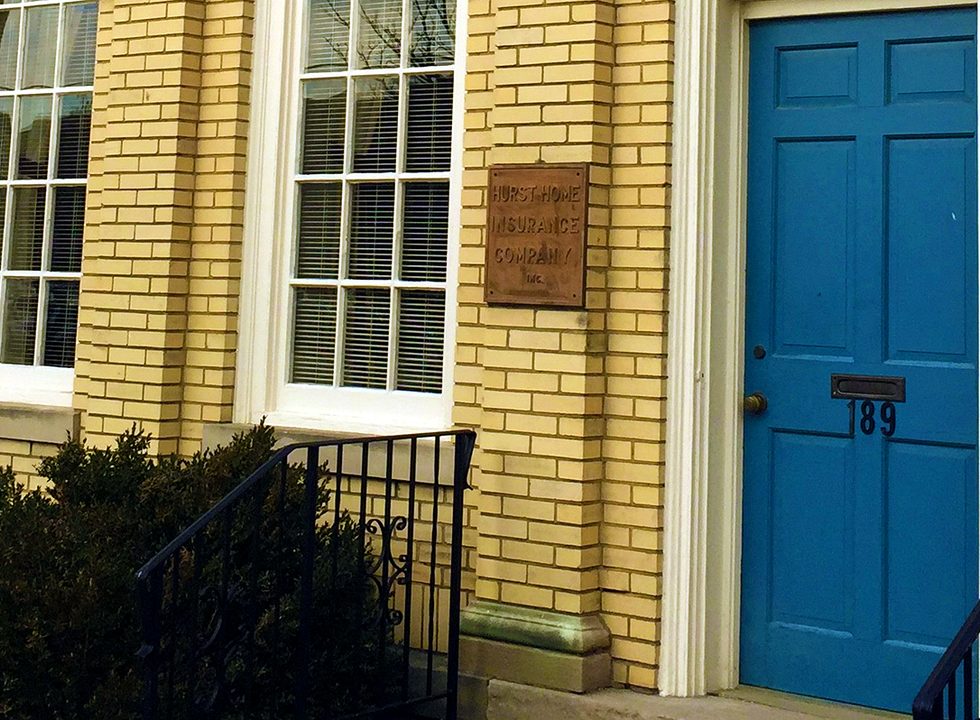 The Hurst Home Insurance office at 189 North Upper Street, Lexington — yellow brick with a teal door and bronze plaques